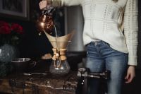 Kaboompics - Woman in a Cream Sweater Brewing Pour-Over Coffee beside Red Roses at a Rustic Table