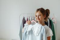 Kaboompics - Teen Girl Smiling with White Eyelet Blouse on Hanger, Clothing Choice at Home