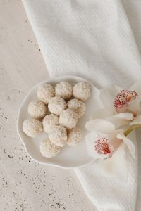 Kaboompics - Overhead Coconut Truffles in a Scalloped Glass Bowl, Pale Stone Background with Left Copy Space