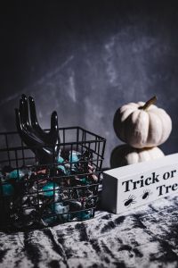 Kaboompics - Skeleton Hand in Candy Basket beside Trick-or-Treat Sign with Dark Copy Space