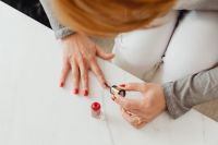 Kaboompics - Overhead View of a Woman Painting Red Nail Polish for At-Home Beauty Content
