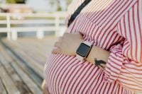 Kaboompics - Pregnant Woman in Striped Dress Wearing Smartwatch on Outdoor Deck