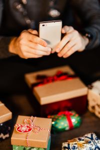 Kaboompics - Man Checking Mobile Phone beside Holiday Gift Boxes
