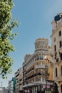 Kaboompics - Vertical Madrid Architecture with Spanish Flag, Cream Facade and Green Tree Framing