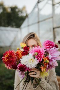 Kaboompics - Woman Peering Over Dahlia Bouquet In Greenhouse