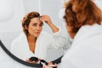 Kaboompics - Middle-Aged Woman Applying a Cotton Pad to Her Forehead During a Bathroom Skincare Routine