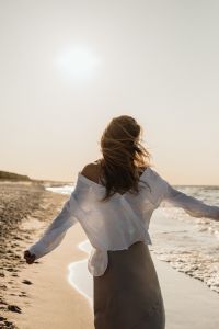 Kaboompics - Faceless Woman Walking by the Sea in White Shirt and Satin Skirt