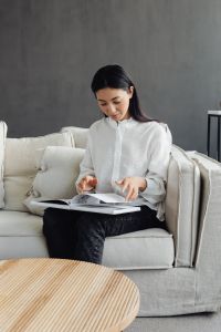 Kaboompics - Woman Reading a Magazine on a White Linen Couch