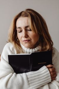 Kaboompics - Woman with Closed Eyes Holding a Holy Bible in Prayer
