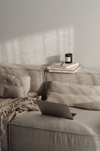 Kaboompics - Sunlit Work From Home Setup with Laptop and Books on a Neutral Sofa
