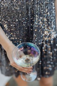 Kaboompics - Overhead Close-Up of Champagne Coupe and Hand over Silver Sequins
