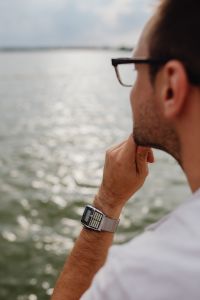 Kaboompics - Man in Black Eyeglasses Looking Over the Lake, Close-Up Portrait with Calculator Watch