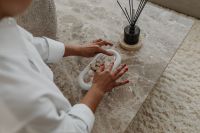 Kaboompics - Woman Styling Seashell Decor on a White Tray at a Marble Coffee Table
