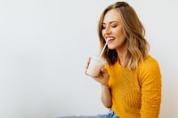 Kaboompics - Smiling Woman Holding a Milkshake in a Yellow Sweater