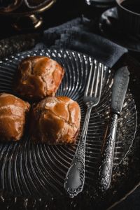 Kaboompics - Sweet Buns, Coffee and Ornate Silverware on a Dark Plate