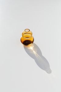 Kaboompics - Sculptural Amber Glass Vase with a Dramatic Sunlit Shadow on White