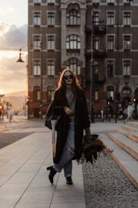 Kaboompics - Woman Carrying an Autumn Bouquet Through a European City Square