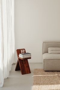 Kaboompics - Wooden Stool with Books and Water Glass beside Gray Sofa and Copy Space