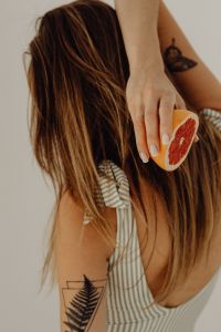 Kaboompics - Woman Holding Grapefruit Beside a Green and White Striped Swimsuit