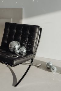 Kaboompics - Black Lounge Chair and Silver Disco Balls Against a Bright Open Wall