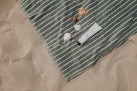 Kaboompics - Striped Beach Towel with Sunglasses, Seashells and Sunscreen