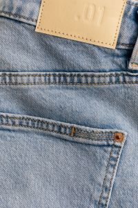 Kaboompics - Vertical Close-Up of Light Wash Jeans Back Pocket with Tan 01 Patch and Copper Rivet