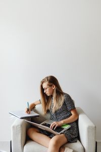 Kaboompics - Student Writing Notes with Laptop in Armchair