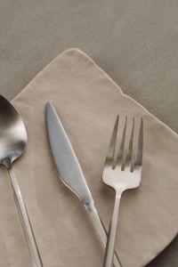 Kaboompics - Matte Steel Spoon, Knife and Fork on a White Napkin and Neutral Surface