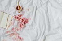 Kaboompics - Pink Roses and Coffee beside Open Notebook on White Bedding with Wide Copy Space