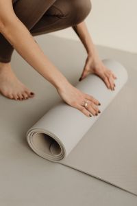 Kaboompics - Woman Rolling a Yoga Mat While Kneeling on the Floor