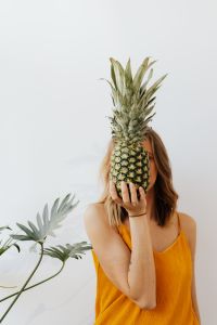 Kaboompics - Pineapple Held above a Woman’s Head with Arms Raised, Playful Food Lifestyle Photo