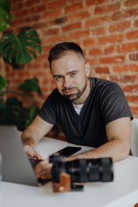 Kaboompics - Photographer Working on Laptop with Camera at Home Office Desk
