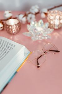 Kaboompics - Diagonal Open Book and Glasses Beside Cotton Stems on Pink Desk