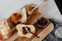 Kaboompics - Overhead Challah Board With Honey and Raspberry Jam Jars