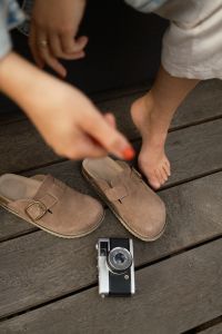 Kaboompics - Vintage Camera On A Wooden Deck Beside Suede Clogs