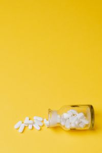 Kaboompics - Side-View Yellow Medicine Bottle with White Pills Spilling Out