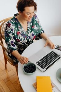Kaboompics - Woman Working on a Laptop with Blueberries at a Round Home Desk