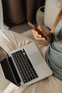 Kaboompics - Work from Home Lifestyle: Woman Checking a Smartphone with a Laptop on Her Lap