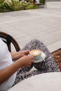 Kaboompics - Woman Holding a Cup of Coffee Beside a Cafe Table