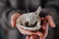 Kaboompics - Hands Holding a Smoking Sage Bundle over a Shell, Home Energy Cleansing Ritual