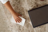 Kaboompics - Close-Up of a Woman Wiping a Marble Table with a White Cloth