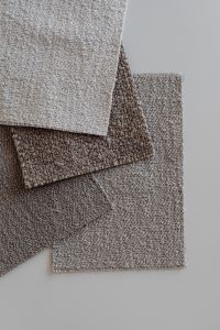 Kaboompics - Layered Neutral Bouclé Upholstery Fabric Swatches on Light Surface