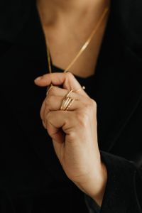 Kaboompics - Woman's Ringed Hand Touching Gold Pendant Necklace