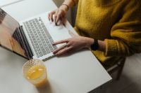 Kaboompics - Hands Typing on a Laptop Beside Orange Juice in a Bright Home Office