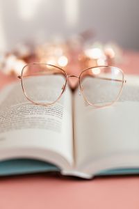 Kaboompics - Close-Up Reading Glasses on an Open Book with Soft Pink Bokeh