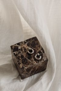 Kaboompics - Chunky Silver Hoop Earrings Styled on a Marble Cube