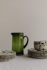 Kaboompics - Green Glass Pitcher with Stacked Green Splatter Tableware