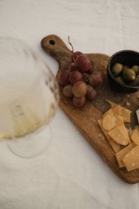Kaboompics - Red Grapes, Cheese Board and Wine Glass on Table