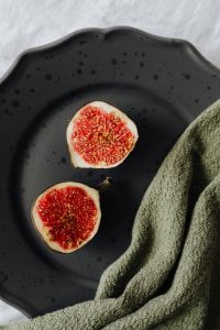 Kaboompics - Close-Up Ripe Fig Halves on a Dark Ceramic Plate, Moody Seasonal Food Photography