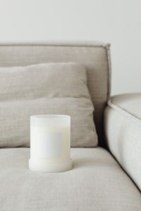 Kaboompics - Close-Up White Candle Mockup Beside a Linen Sofa Cushion